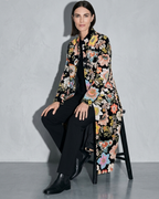 Women's Black Printed Velvet Long Coat, stool, forearms on thighs, worn by model