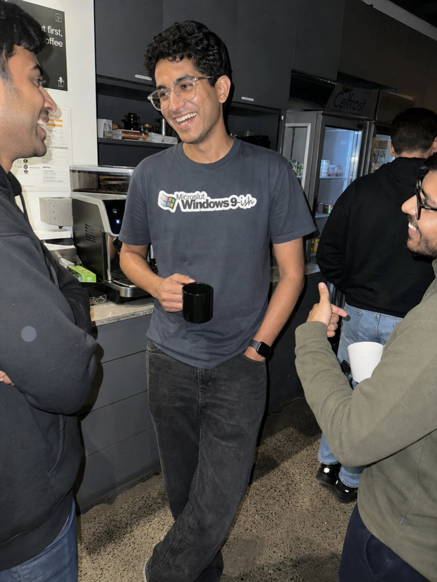 Developer holding a mug in the gray Windows 9-ish tee