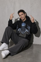 Men's black defiant skeleton graphic hoodie seated view