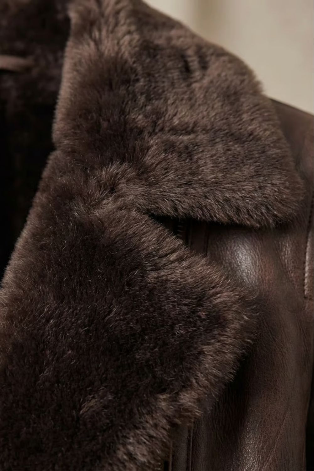 Close-up of brown shearling collar on a leather jacket, soft textured trim