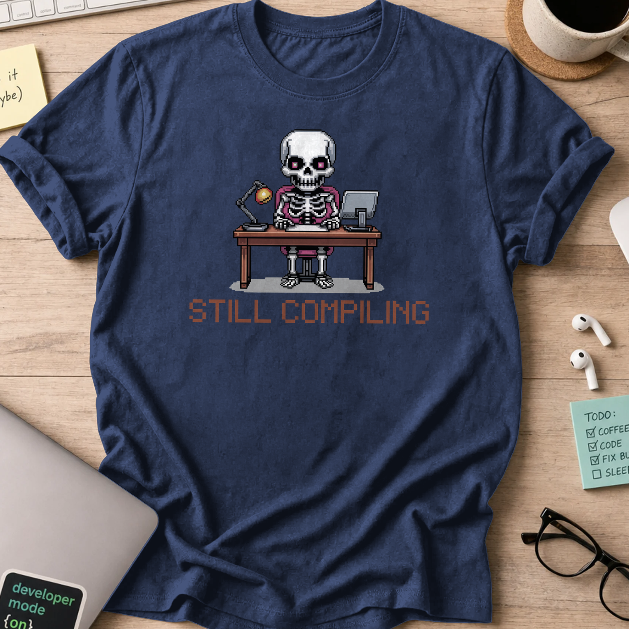 Navy programmer shirt printed with "still compiling skeleton", a funny developer t-shirt and coding gift for software engineers and coders.