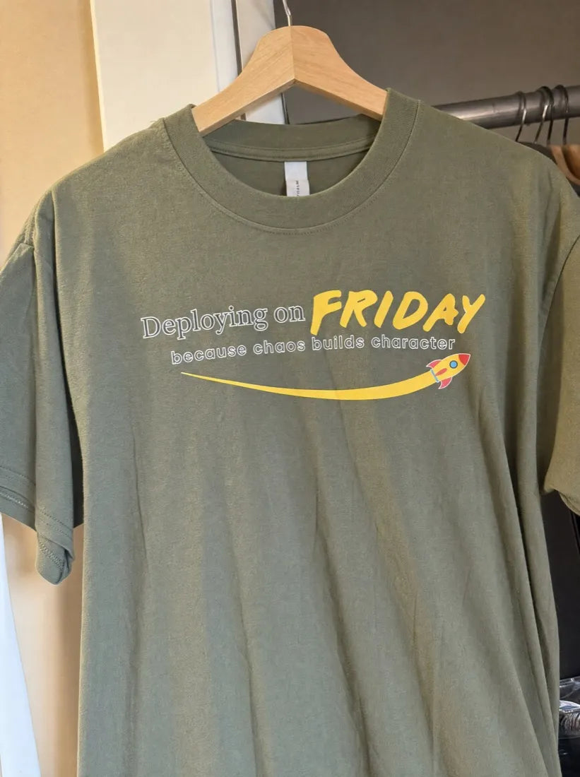 CodeCulture Deploying on Friday t-shirt hanging on a wooden hanger in a casual home